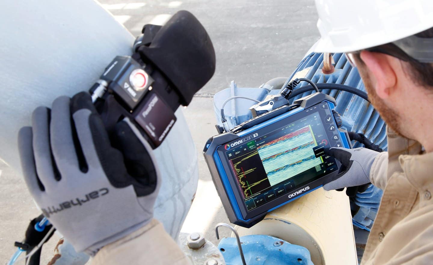 Technik používá senzor a tablet k testování průmyslového potrubí.
